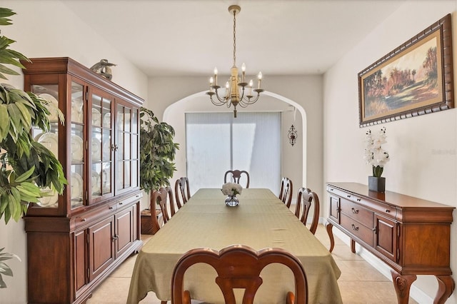 dining space with light tile patterned floors, arched walkways, a healthy amount of sunlight, and an inviting chandelier