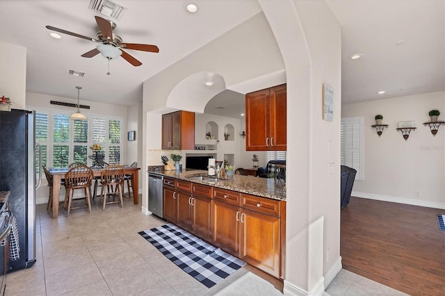 kitchen with stainless steel appliances, brown cabinets, visible vents, and hanging light fixtures