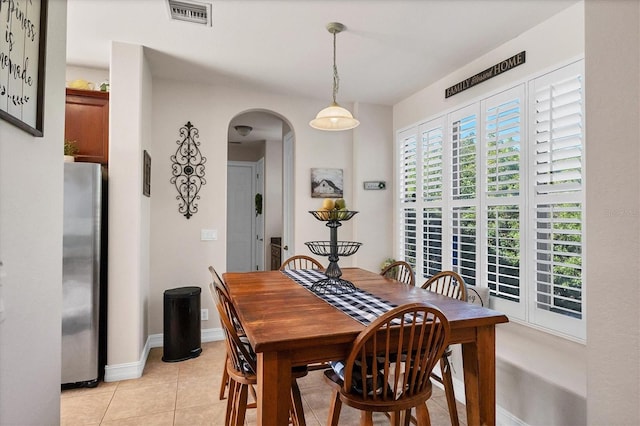 dining space featuring arched walkways, visible vents, baseboards, and light tile patterned floors