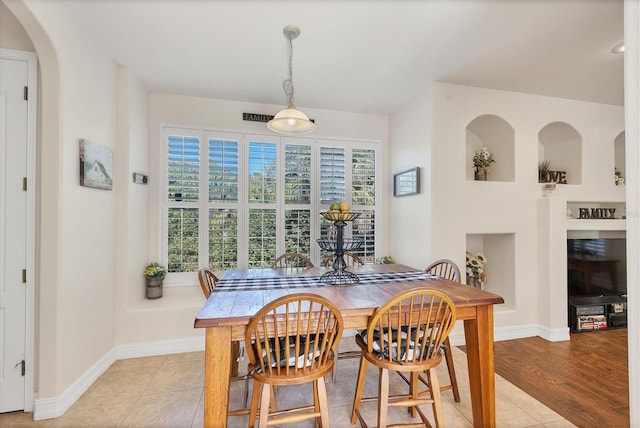 dining room with arched walkways, light tile patterned flooring, and baseboards