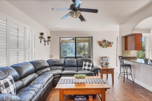 living room featuring a ceiling fan, visible vents, dark wood finished floors, and arched walkways