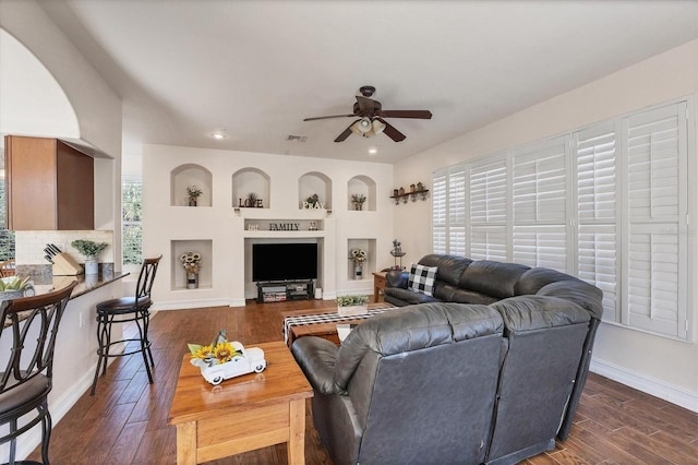 living area featuring a healthy amount of sunlight, dark wood-style floors, baseboards, and visible vents