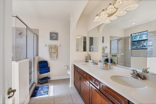 bathroom featuring toilet, a stall shower, tile patterned flooring, and a sink