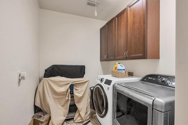 clothes washing area with visible vents, washing machine and dryer, and cabinet space