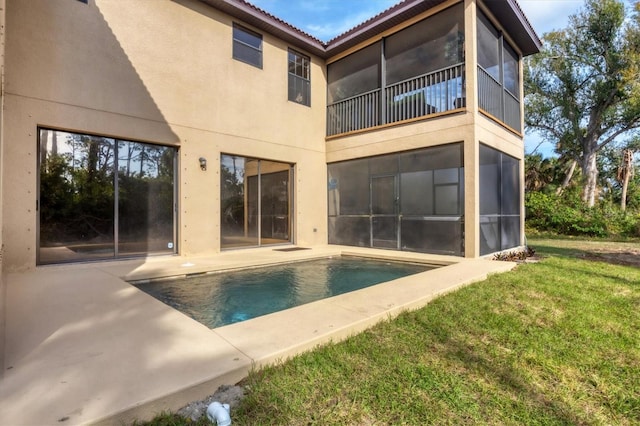 rear view of house featuring a patio area, an outdoor pool, a lawn, and stucco siding