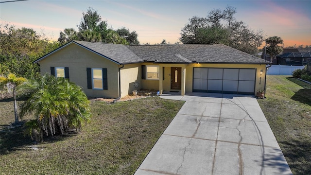 ranch-style home featuring a garage and a yard