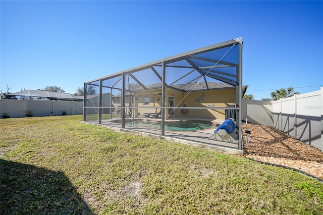 back of house with a fenced in pool, a yard, glass enclosure, and a patio area