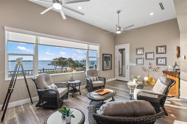 living room featuring hardwood / wood-style flooring, ceiling fan, and a water view