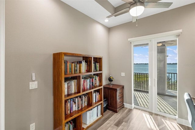 interior space with ceiling fan, a water view, and light wood-type flooring