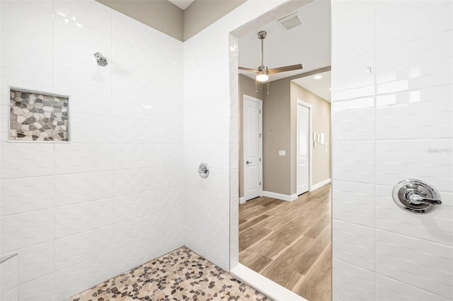 bathroom featuring hardwood / wood-style flooring, tiled shower, and ceiling fan