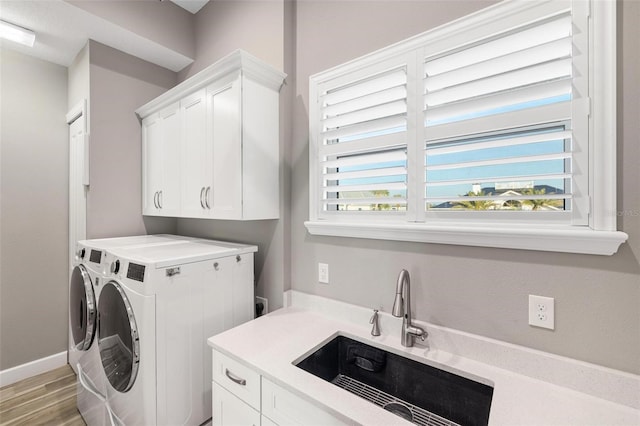 laundry area featuring cabinets, a healthy amount of sunlight, sink, and washing machine and clothes dryer