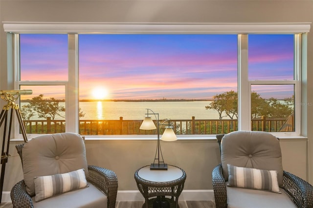 sitting room featuring wood-type flooring, a water view, and a healthy amount of sunlight