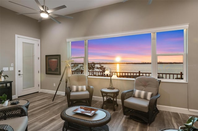 sitting room featuring wood-type flooring, a water view, a healthy amount of sunlight, and ceiling fan