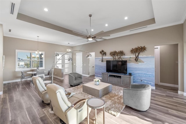 living room featuring crown molding, hardwood / wood-style flooring, and a raised ceiling