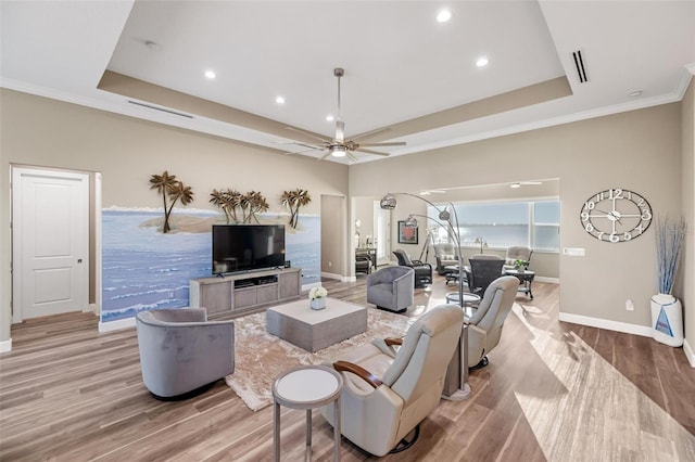 living room featuring a raised ceiling, ceiling fan, and light hardwood / wood-style floors