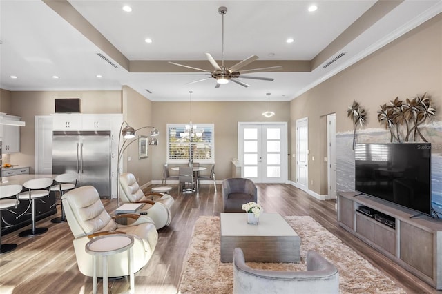 living room with crown molding, hardwood / wood-style floors, a tray ceiling, and french doors