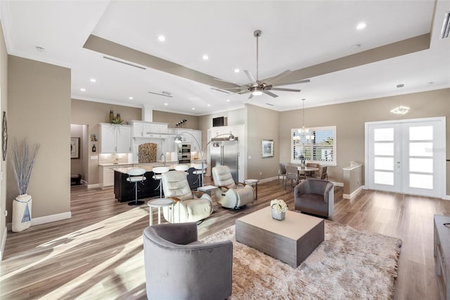 living room with french doors, ornamental molding, sink, and light hardwood / wood-style flooring