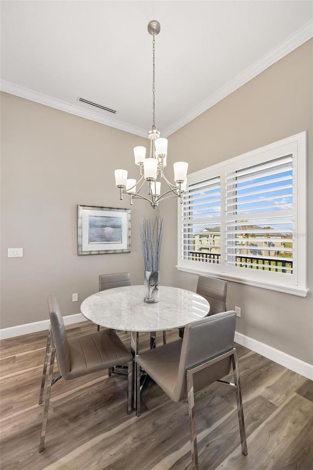 dining room featuring a notable chandelier, crown molding, and hardwood / wood-style flooring