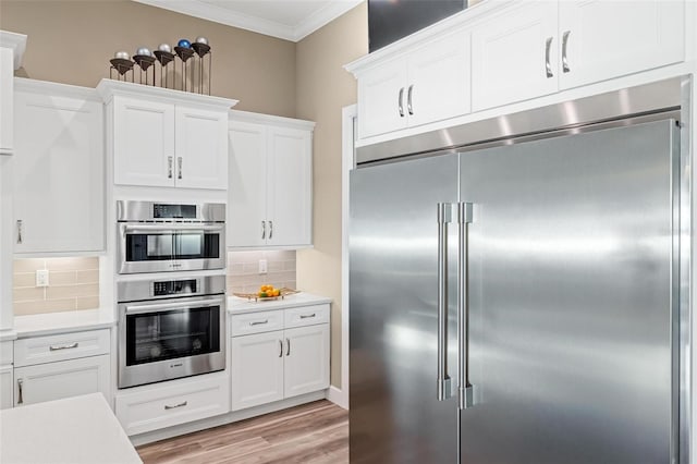 kitchen with crown molding, appliances with stainless steel finishes, tasteful backsplash, and white cabinets