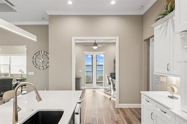 kitchen with sink, crown molding, ceiling fan, light hardwood / wood-style floors, and white cabinets