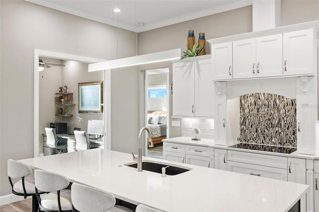 kitchen with white cabinetry, sink, a center island with sink, and black electric stovetop