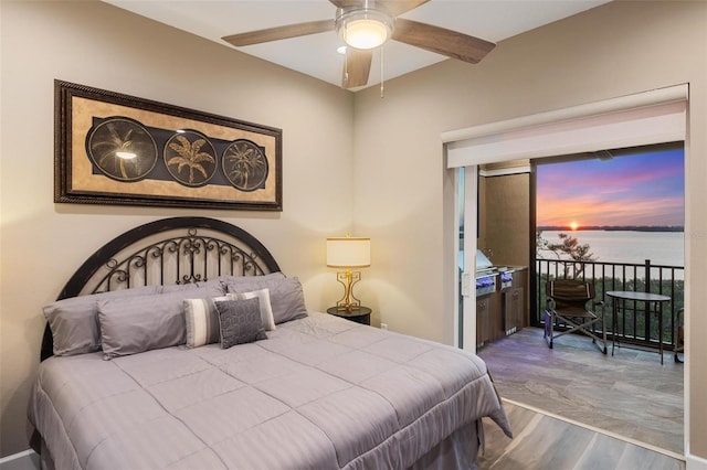 bedroom with hardwood / wood-style floors and a water view