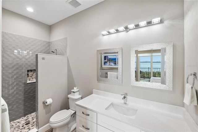 bathroom featuring vanity, toilet, and a tile shower