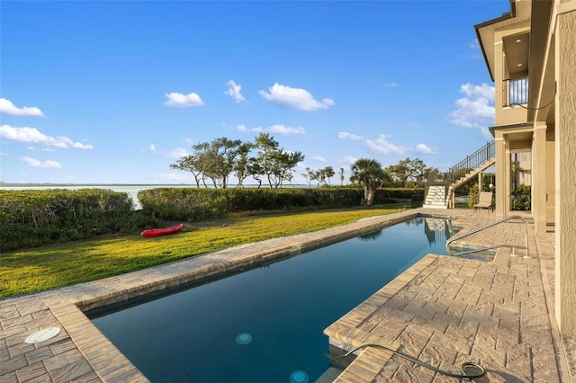 view of swimming pool with a lawn and a water view