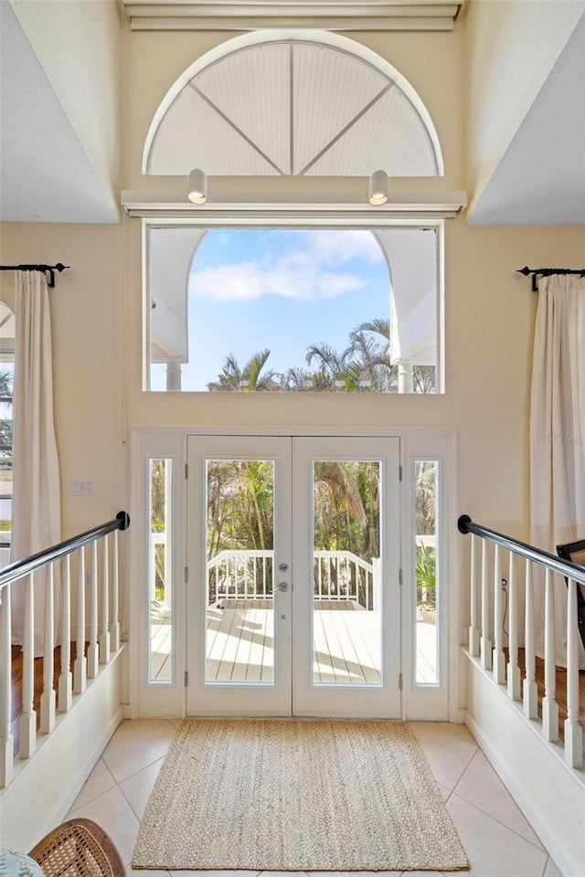 doorway to outside featuring a healthy amount of sunlight, a high ceiling, and light tile patterned floors