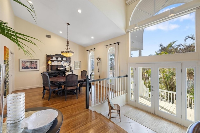 dining area featuring light hardwood / wood-style floors, high vaulted ceiling, and french doors