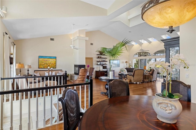 dining room with hardwood / wood-style flooring, ceiling fan, and high vaulted ceiling