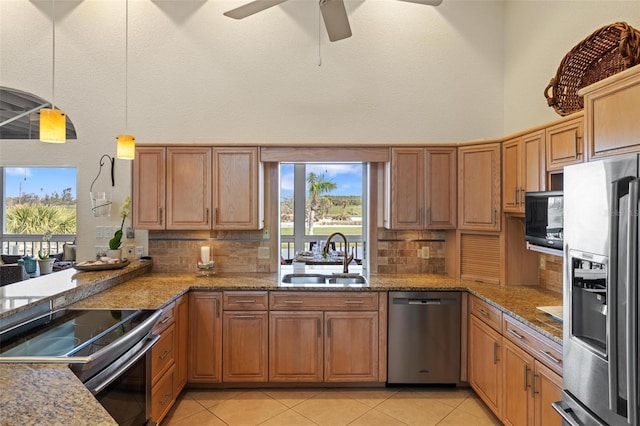 kitchen with sink, tasteful backsplash, pendant lighting, stainless steel appliances, and a high ceiling