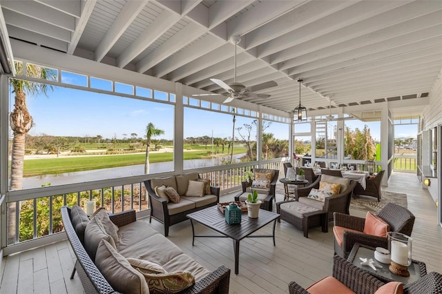 sunroom with ceiling fan and a water view