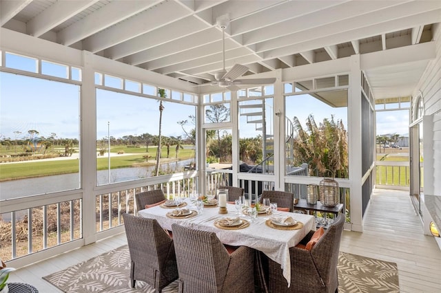 sunroom featuring ceiling fan and a water view