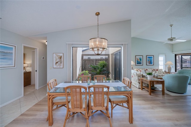 dining room featuring ceiling fan with notable chandelier, vaulted ceiling, and light wood-type flooring