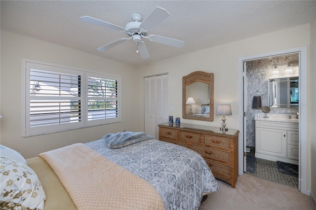 carpeted bedroom featuring ceiling fan, a closet, a textured ceiling, and ensuite bathroom