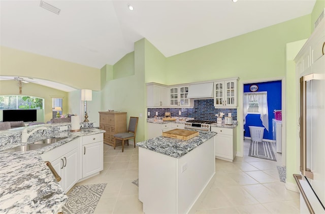 kitchen featuring white cabinetry, sink, light stone countertops, and a kitchen island