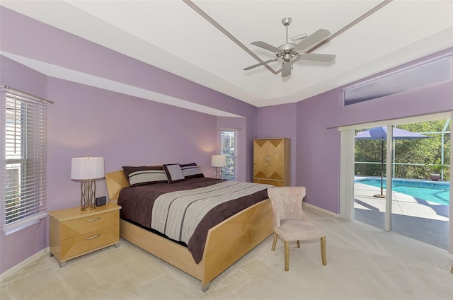 carpeted bedroom with multiple windows, a tray ceiling, access to outside, and ceiling fan