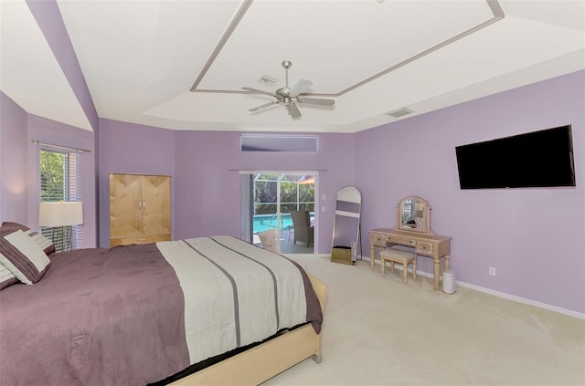 carpeted bedroom with access to exterior, ceiling fan, and a tray ceiling