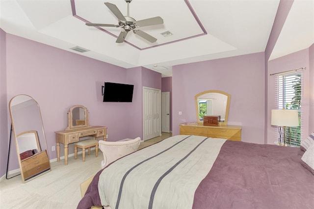 bedroom featuring ceiling fan, light colored carpet, and a raised ceiling