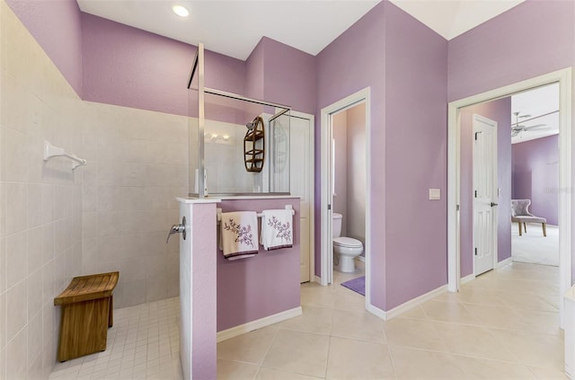 bathroom with tile patterned flooring, toilet, and tiled shower