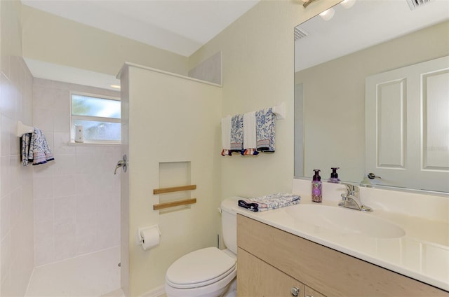 bathroom with vanity, a tile shower, and toilet