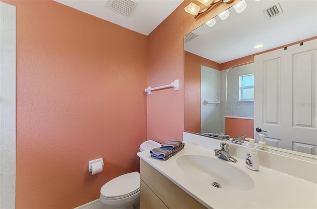 bathroom with vanity, a tile shower, and toilet