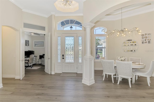 entrance foyer with crown molding, ceiling fan with notable chandelier, decorative columns, and hardwood / wood-style floors