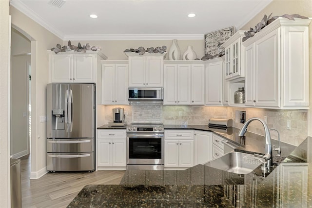 kitchen with sink, crown molding, appliances with stainless steel finishes, dark stone countertops, and white cabinets