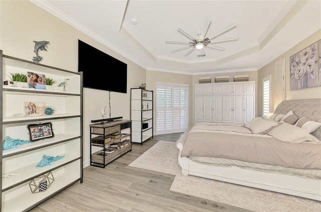 bedroom with a raised ceiling, ornamental molding, multiple windows, and light hardwood / wood-style floors