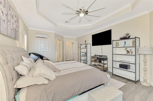 bedroom featuring crown molding, a wall mounted air conditioner, a raised ceiling, and light hardwood / wood-style flooring