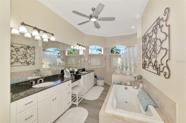 bathroom featuring hardwood / wood-style flooring, ceiling fan, vanity, a relaxing tiled tub, and ornamental molding