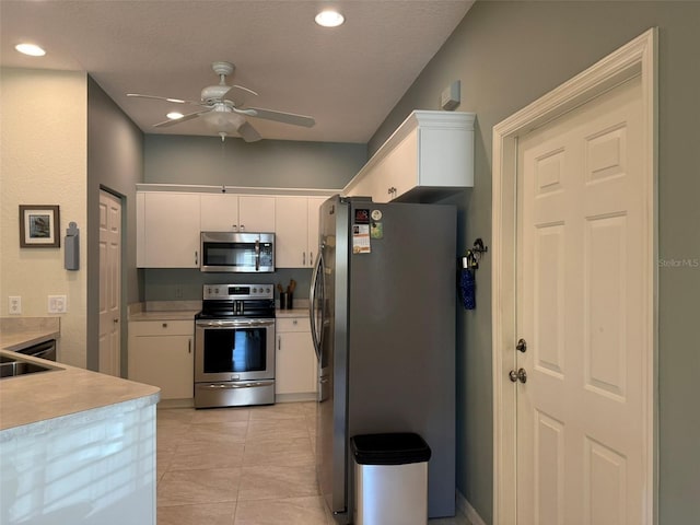 kitchen featuring light tile patterned floors, ceiling fan, white cabinetry, stainless steel appliances, and a textured ceiling