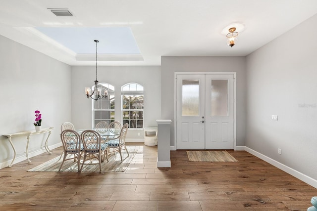 dining area featuring a notable chandelier, a tray ceiling, and dark hardwood / wood-style floors